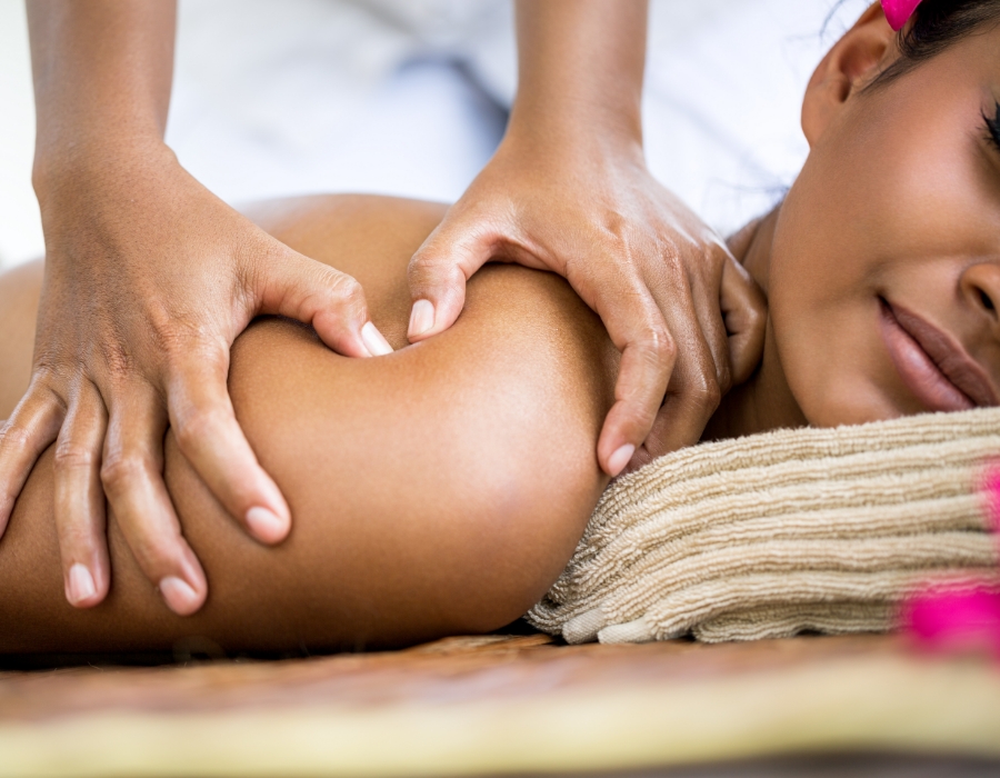Chiropractor giving Message-therapy to patients back and shoulders. Patient is lying on their stomach looking relaxed and happy.
