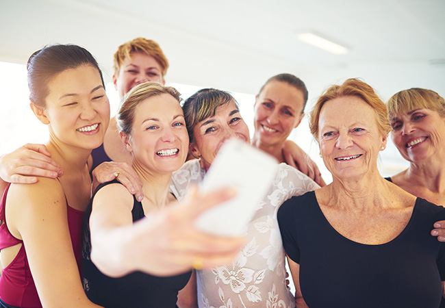 Group of women taking a selfie together smiling.