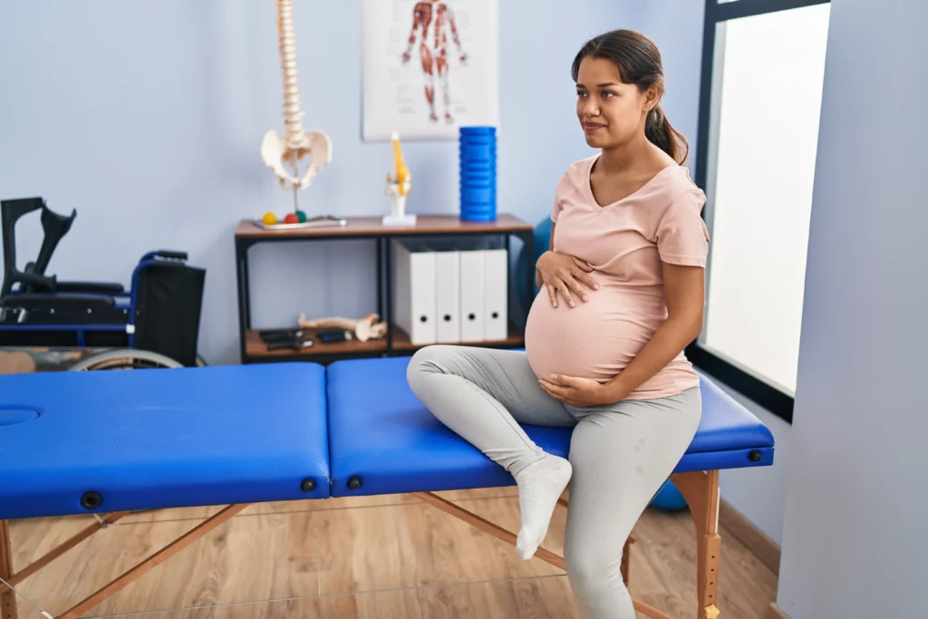 Pregnant woman on a table in a medical room, undergoing the Webster Technique for pelvic alignment and fetal positioning.
A pregnant woman seated on a table in a clinical setting, ready for a Webster Technique chiropractic adjustment.