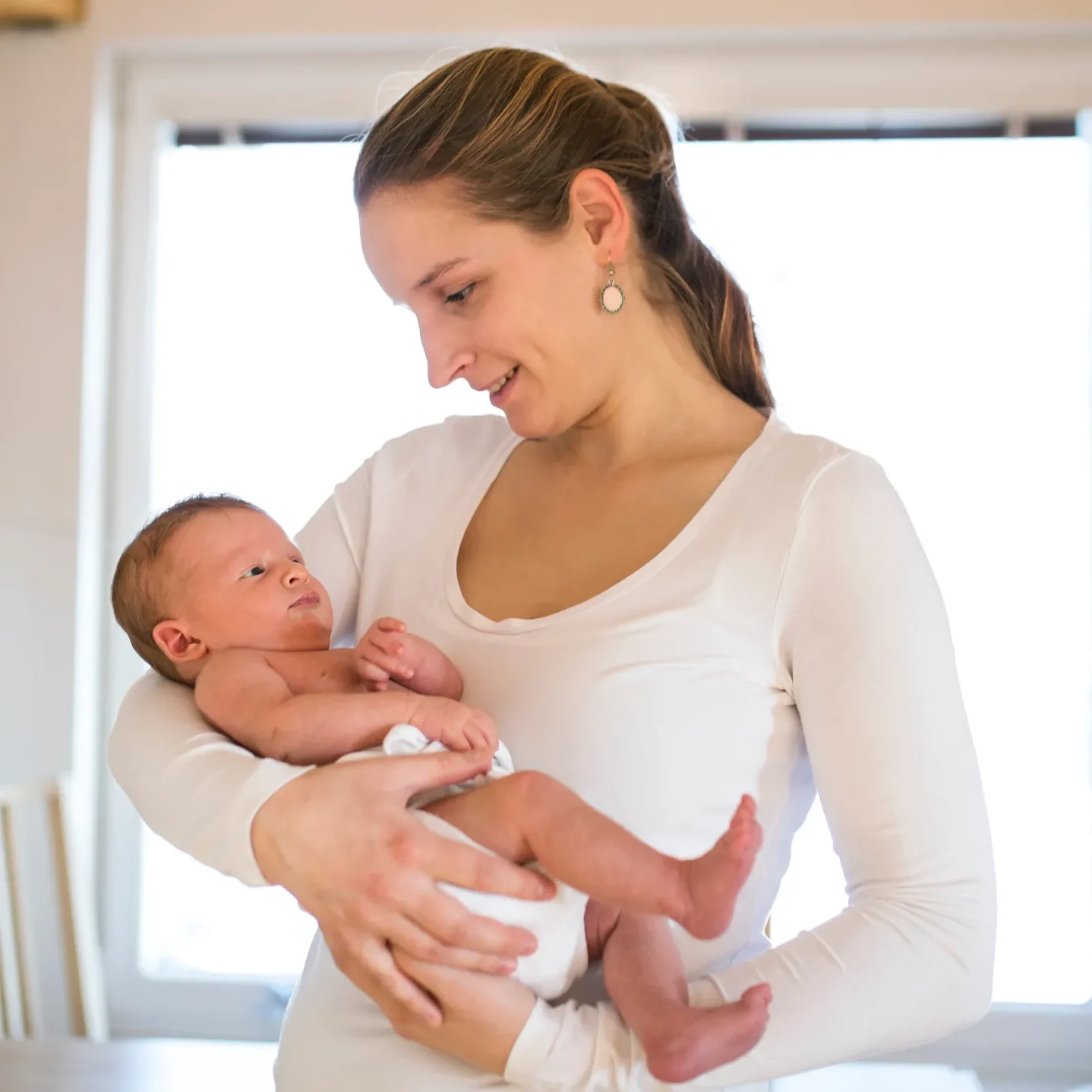 A woman cradles a baby in her arms, symbolizing the postpartum journey and the importance of chiropractic care for recovery.