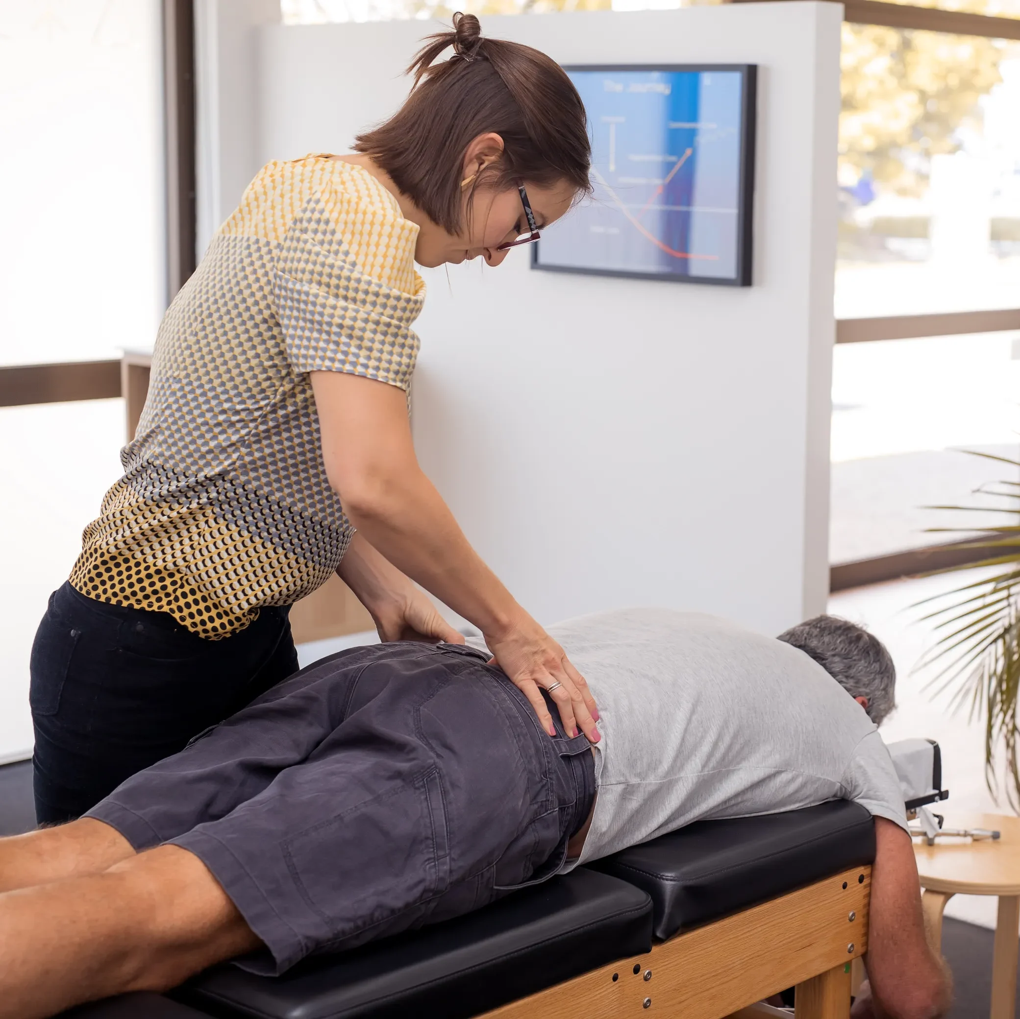 Chiropractor making adjustments to patients back giving care at MCR Clinic.