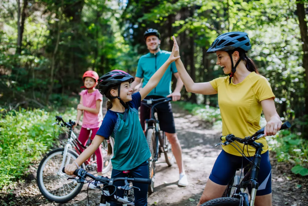 Family of four being active together outside for a bike ride in the woods spring 2025.