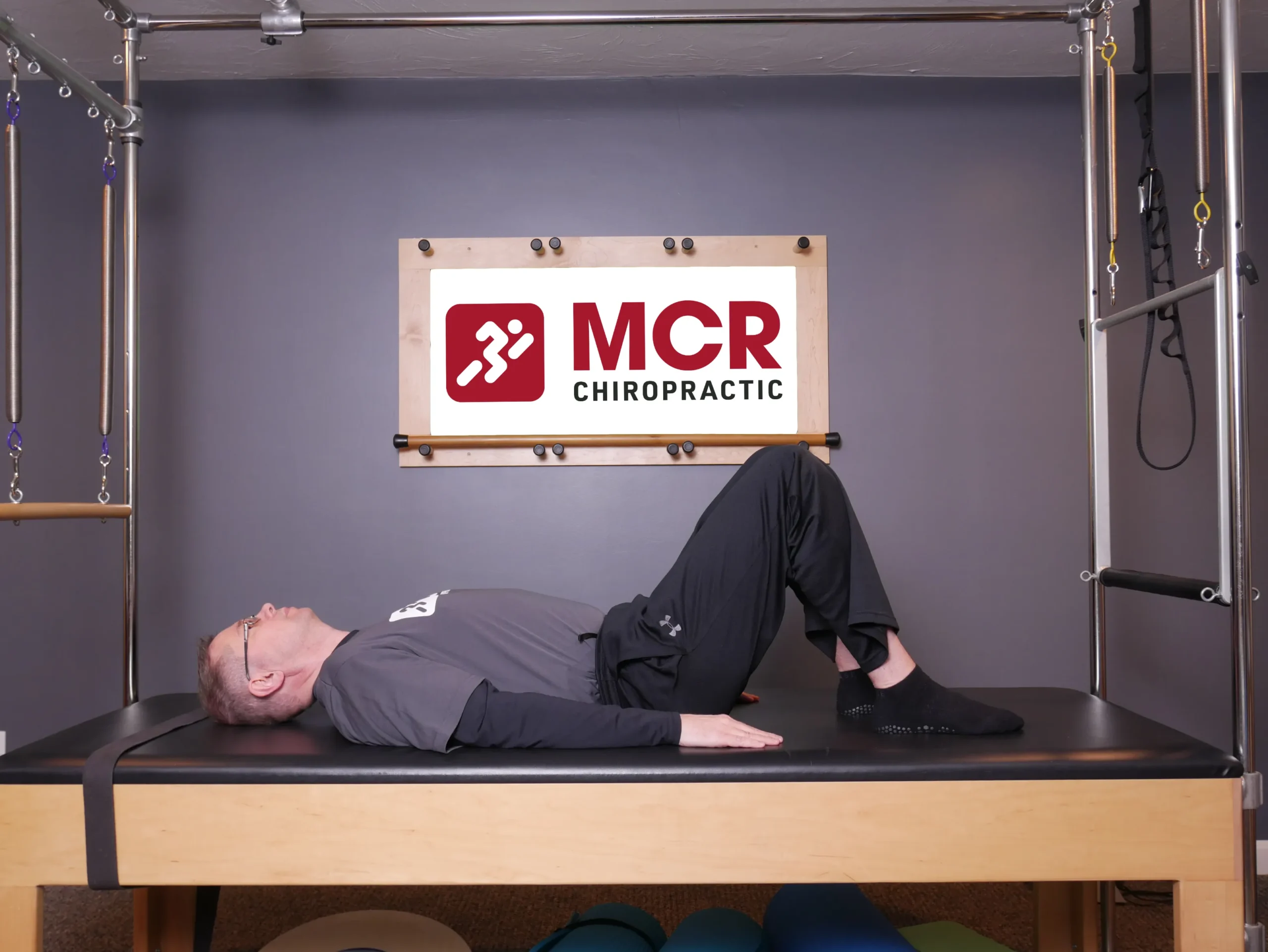 Man laying on his back on the table with his knees up demonstrating the Bridges exercise.
