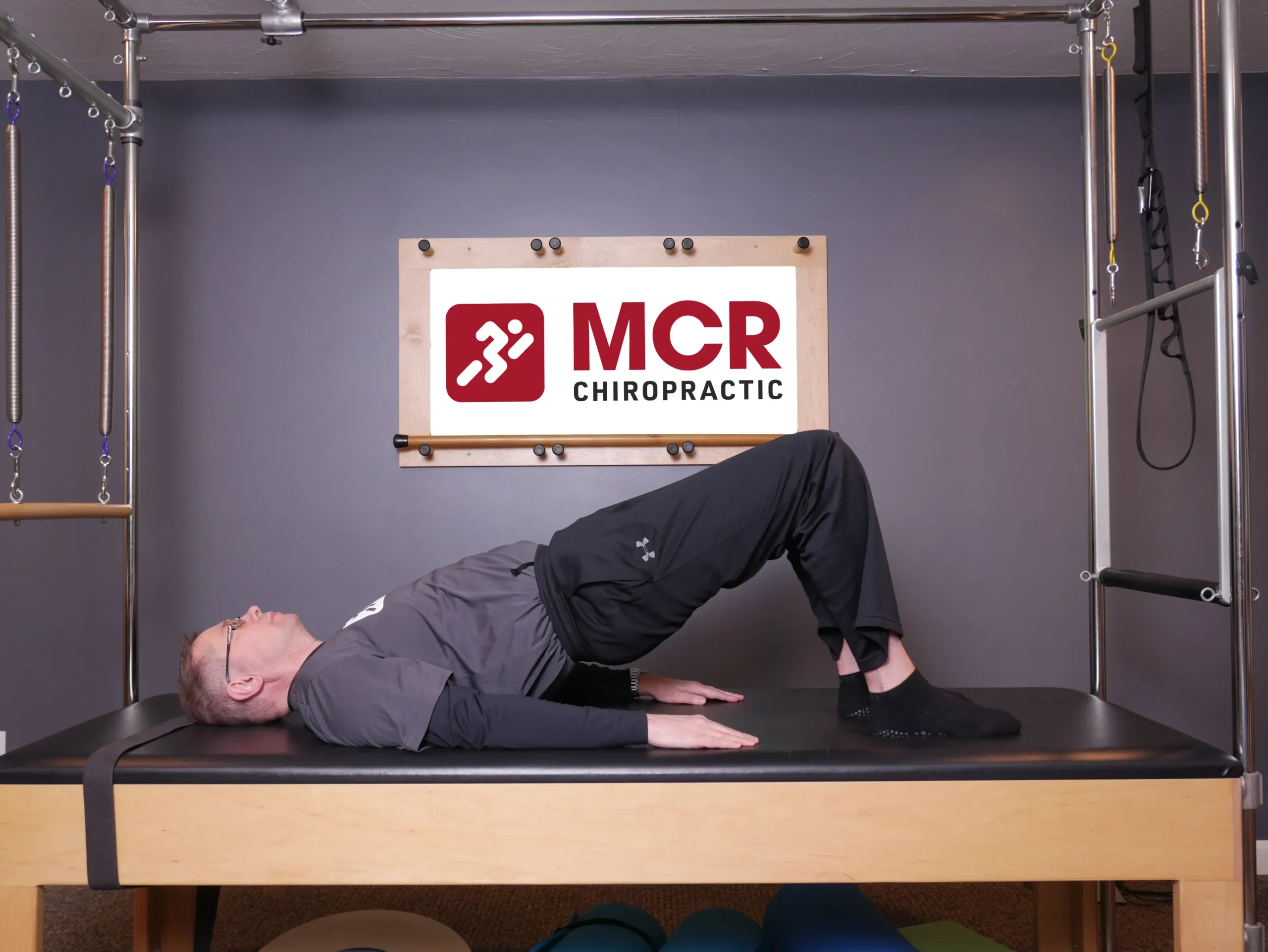 Man laying on his back on the table with his knees up demonstrating the Bridges exercise.