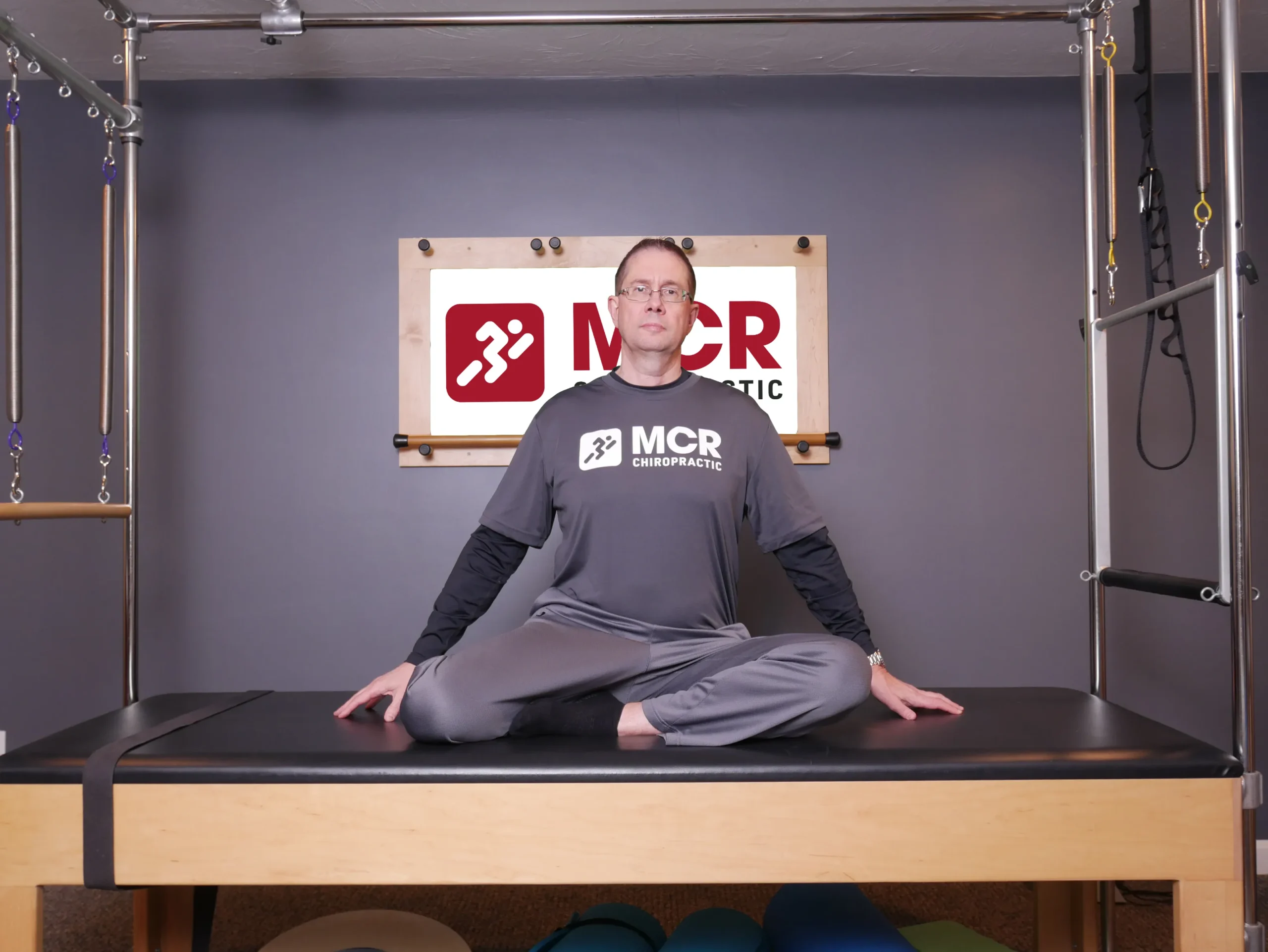 Man seated on table, demonstrating the mermaid stretch.