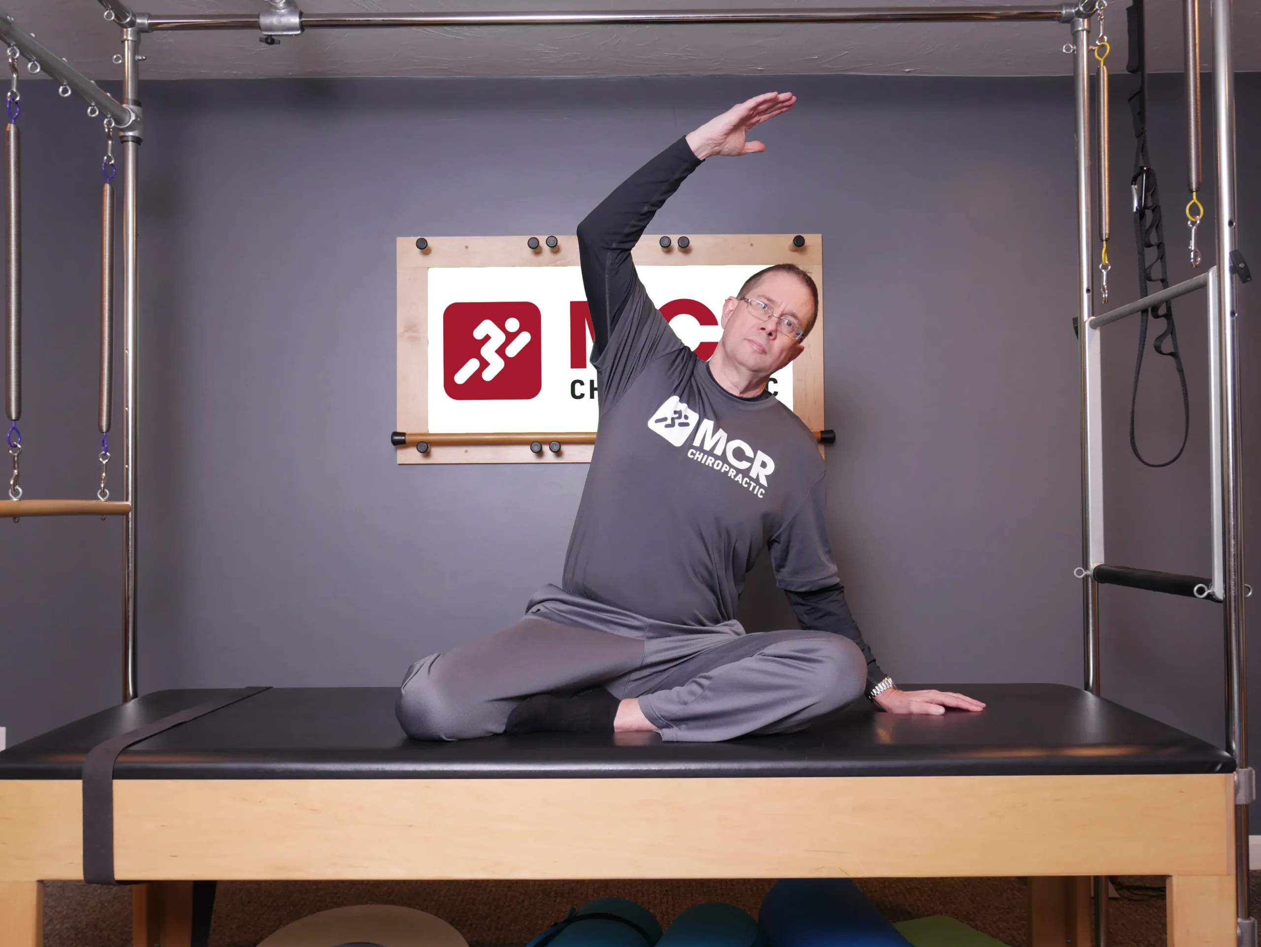 Man seated on table, demonstrating the mermaid stretch.