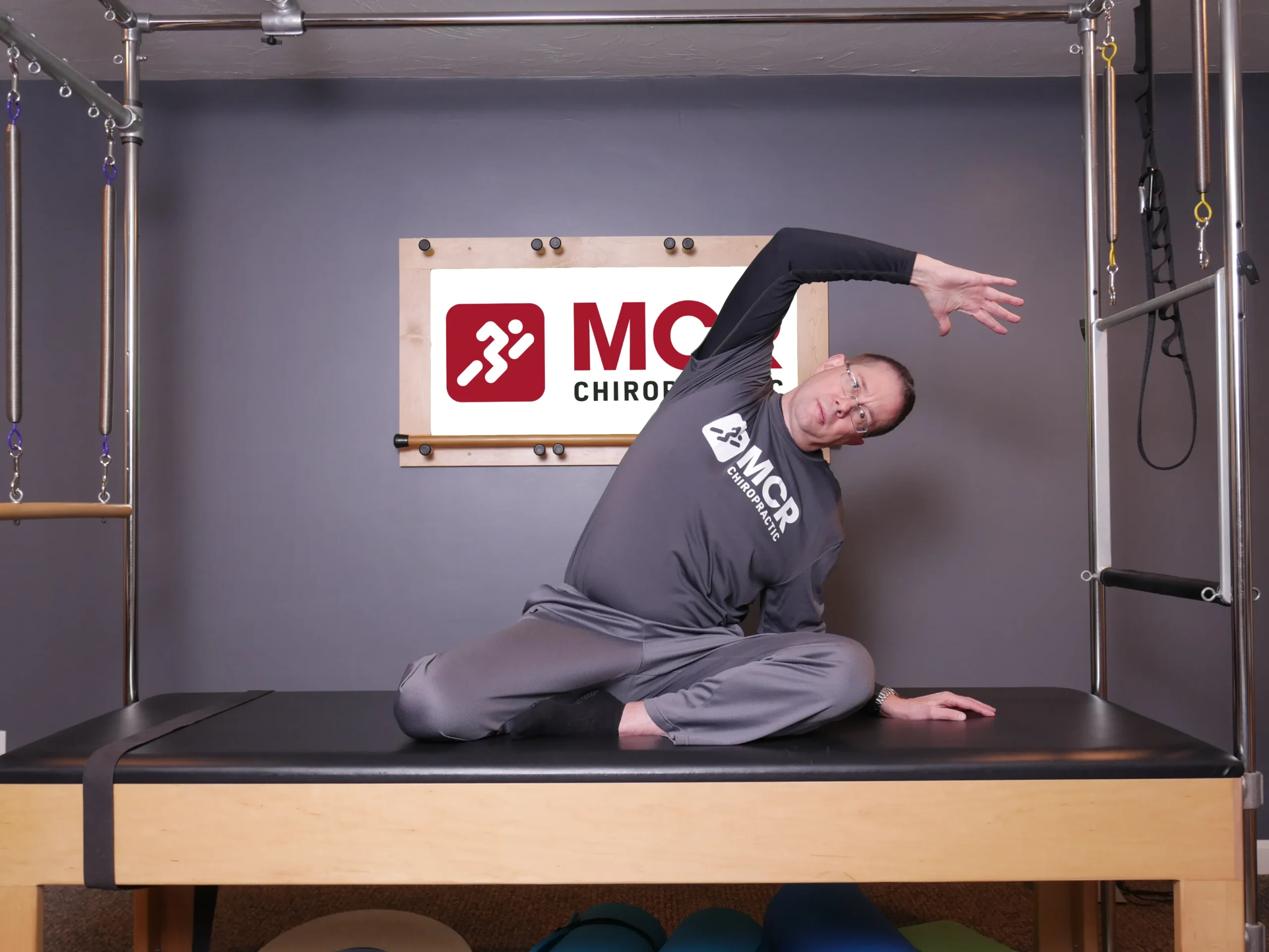 Man seated on table, demonstrating the mermaid stretch.