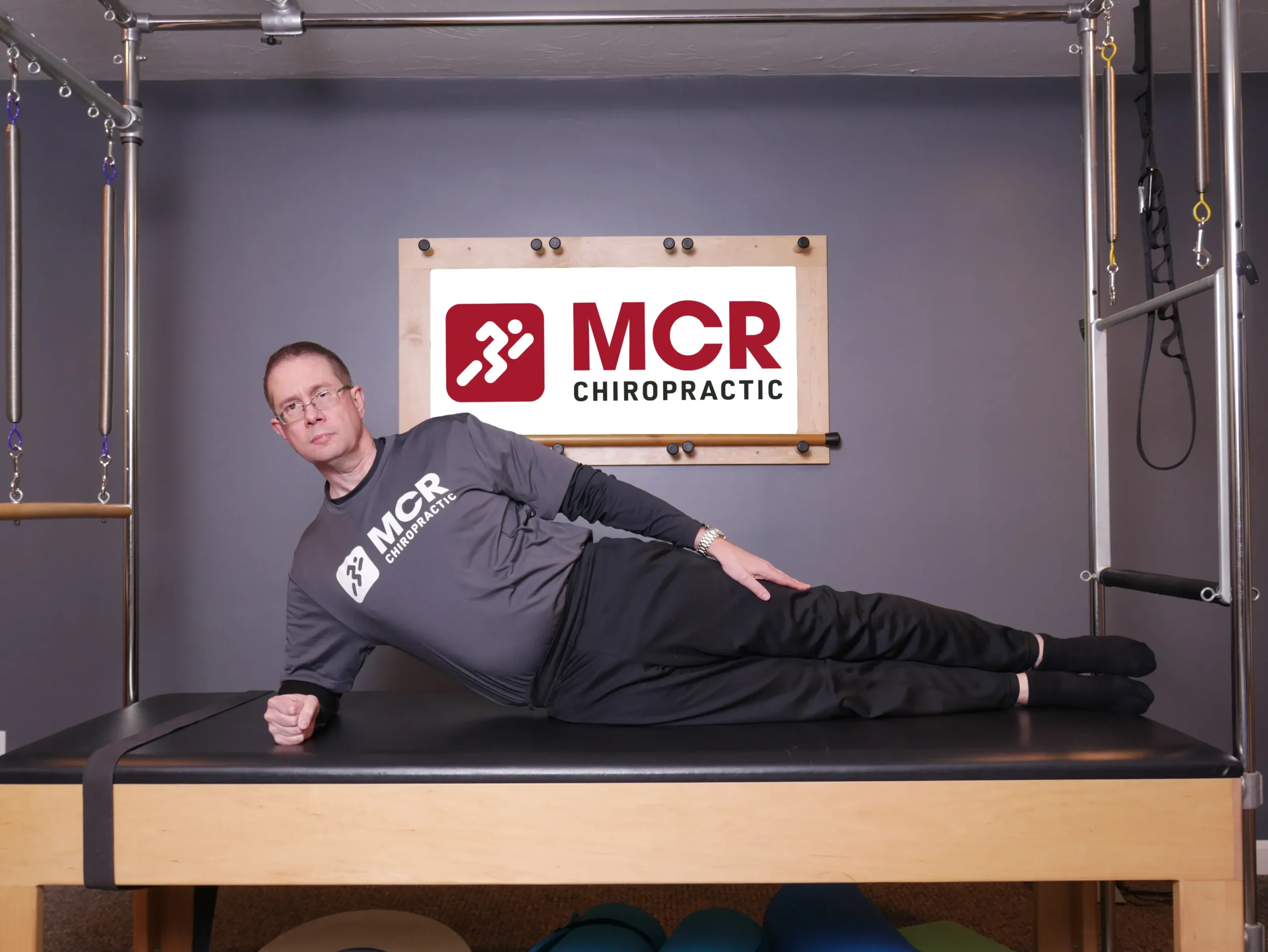 Man laying on the table on one side demonstrating the sidekick exercise.
