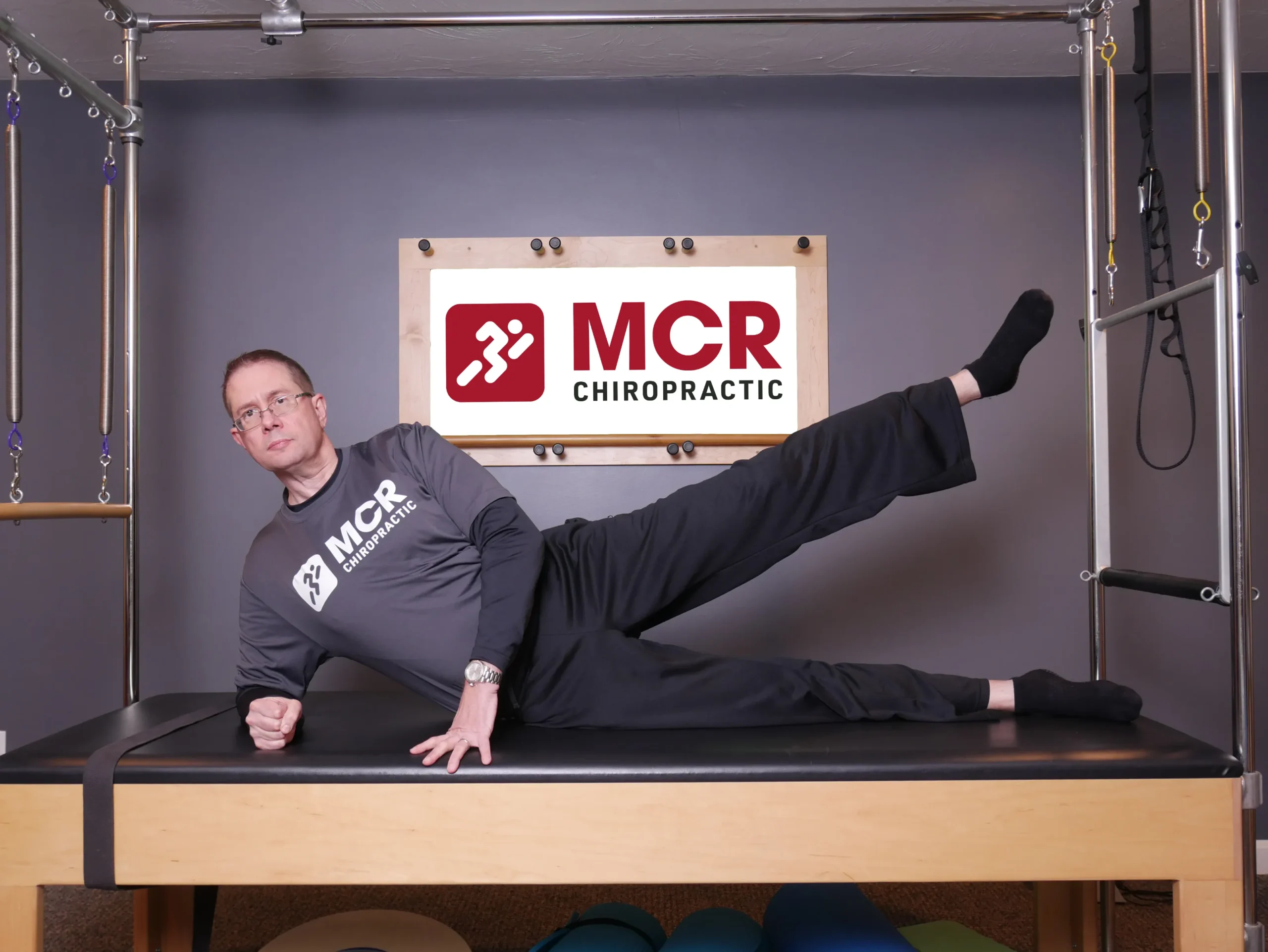 Man laying on the table on one side demonstrating the sidekick exercise.