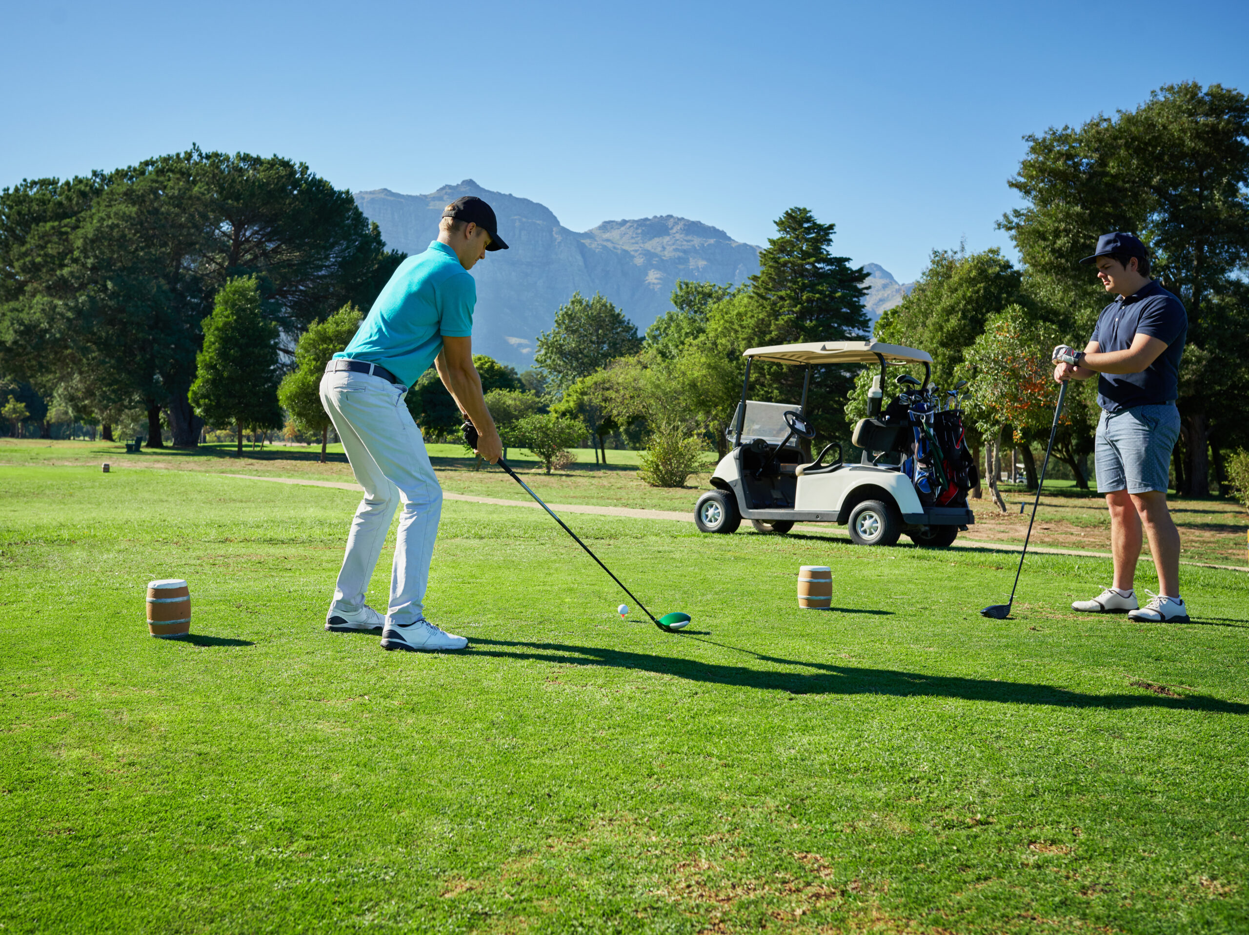 Shot of two focused young men playing a game of golf outside on a golf course.